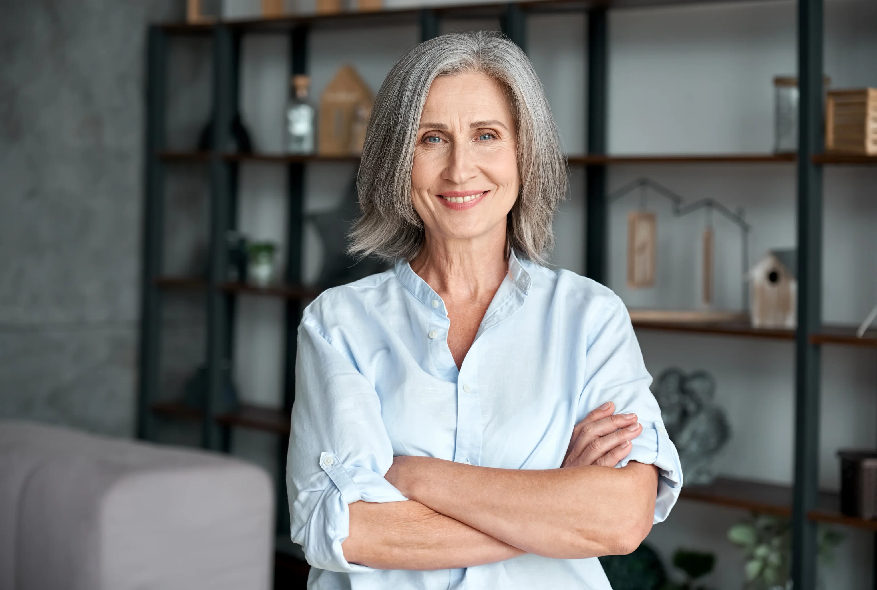 Confident woman standing with arms crossed in a modern living room