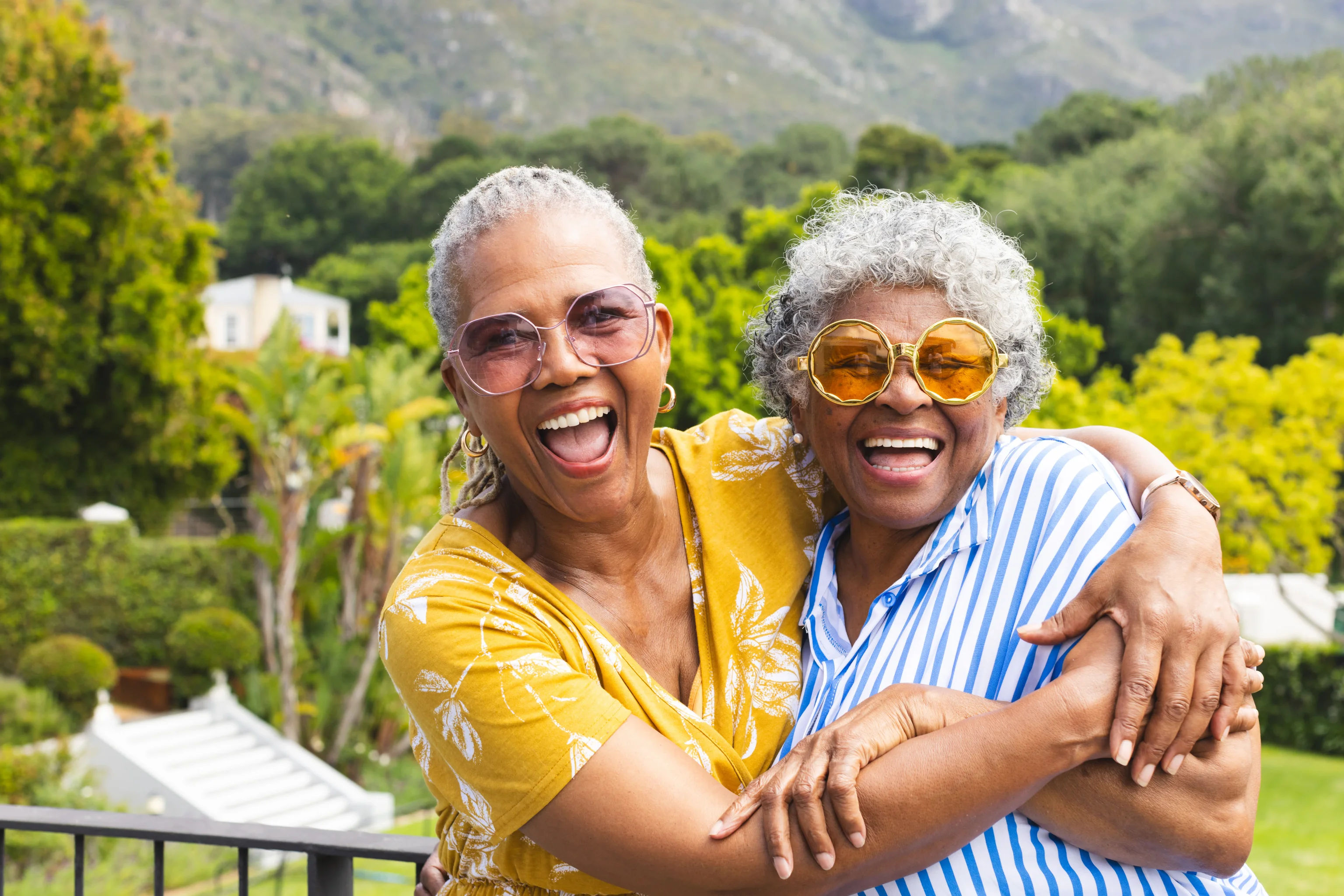 Two smiling friends embracing outdoors in a garden