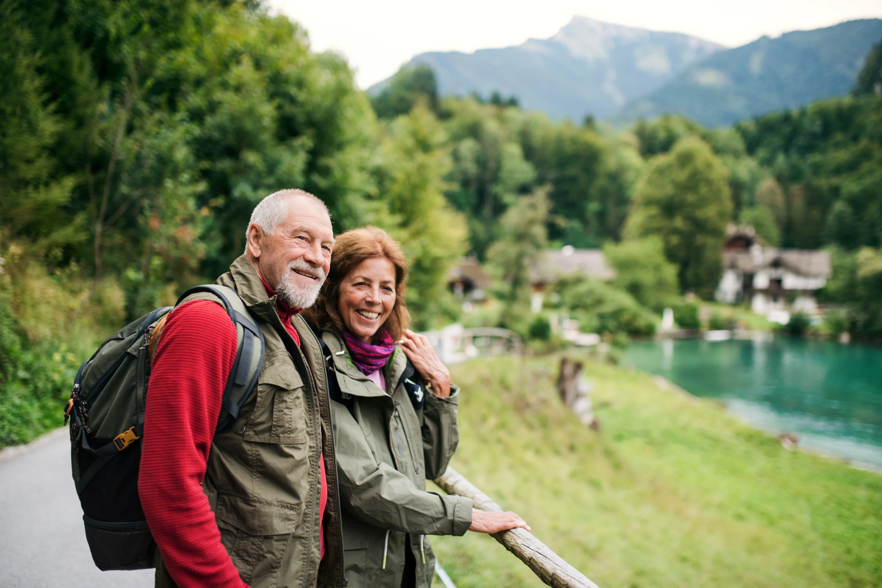 Smiling couple hiking beside a mountain lake