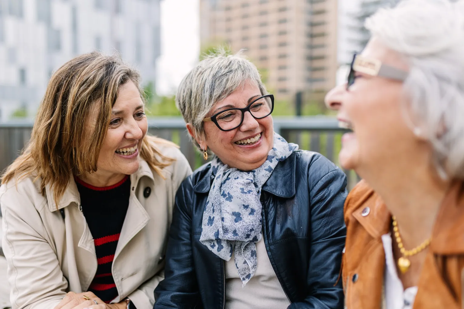Three friends laughing together outdoors (actor portrayal)